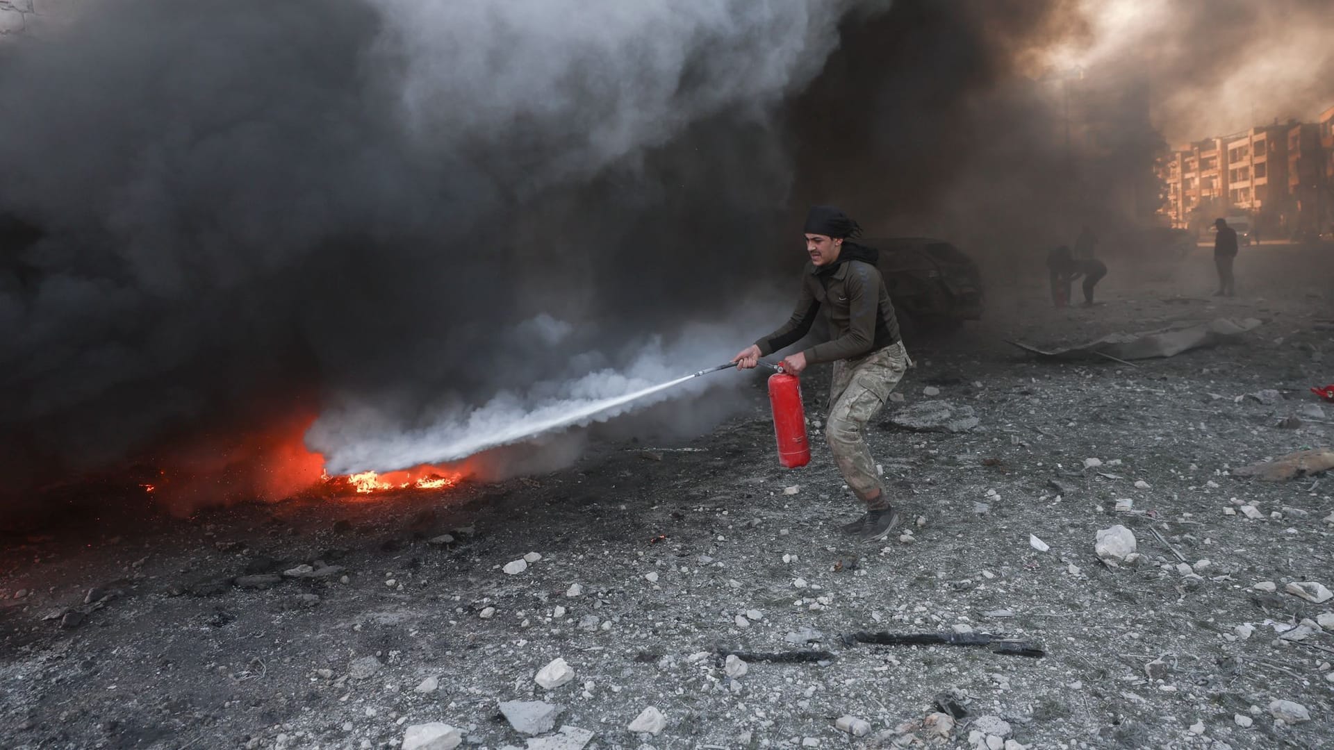 Ein Mann in Idlib versucht, das durch einen Luftangriff verursachte Feuer vor einem Krankenhauskomplex zu löschen.