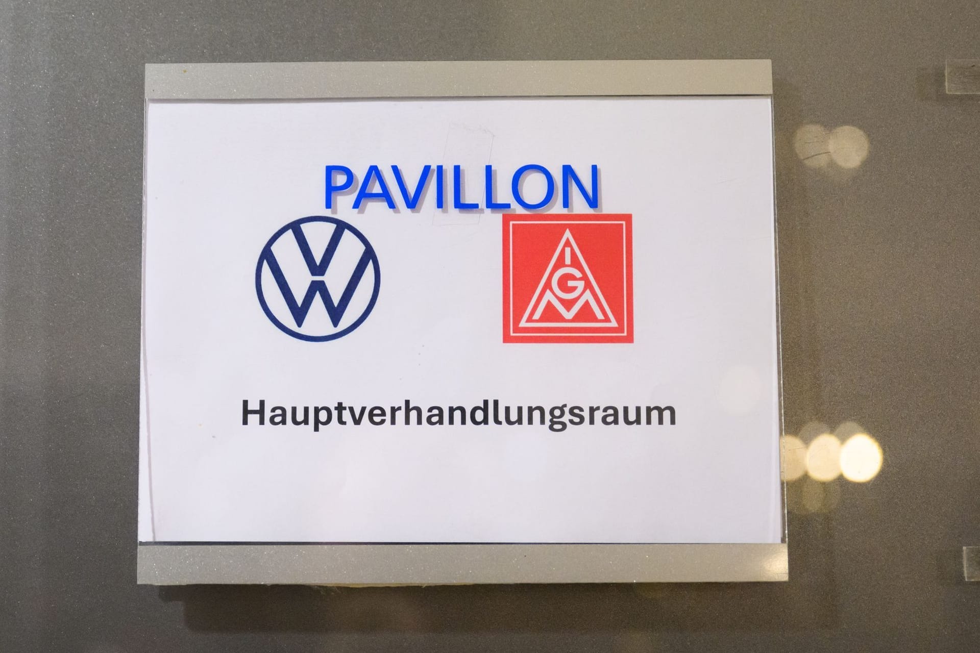 Ein Schild mit der Aufschrift "Hauptverhandlungsraum" und den Logos der IG Metall und Volkswagen: Seit Montag ringen beide Parteien um eine Einigung im Tarifstreit.