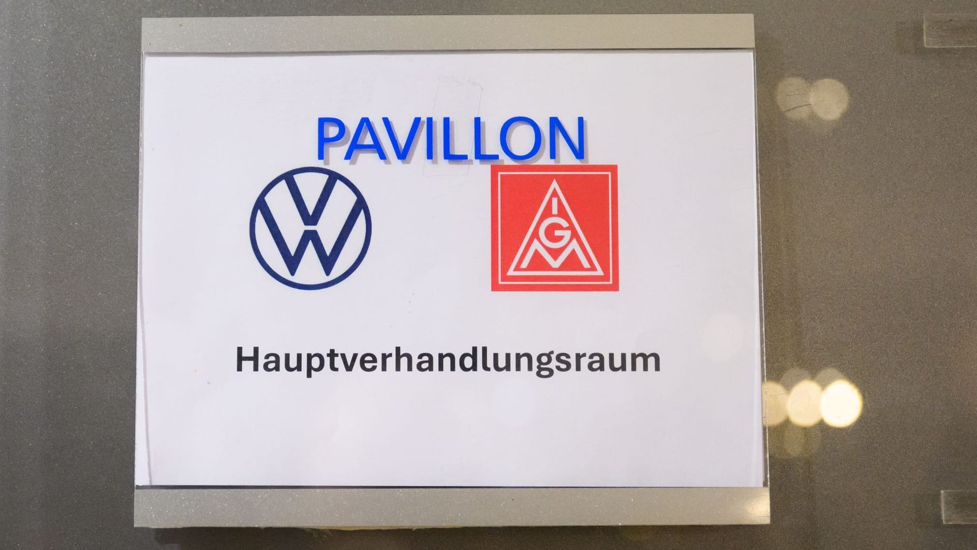 Ein Schild mit der Aufschrift "Hauptverhandlungsraum" und den Logos der IG Metall und Volkswagen: Seit Montag ringen beide Parteien um eine Einigung im Tarifstreit.