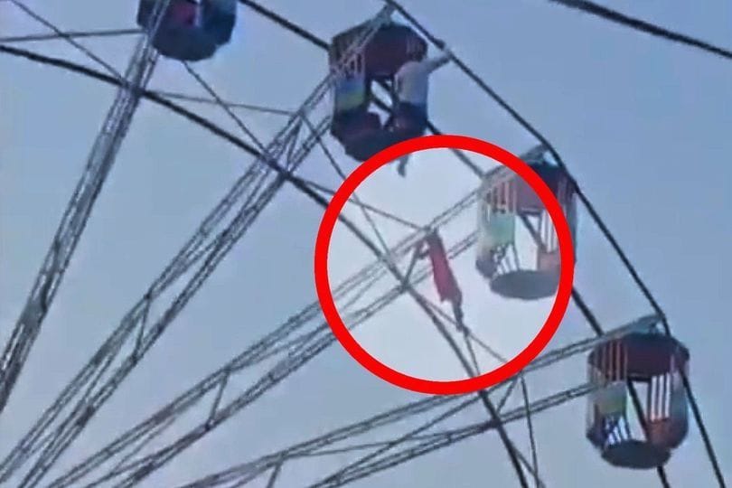 Ein Mädchen klammert sich an einem Riesenrad fest.