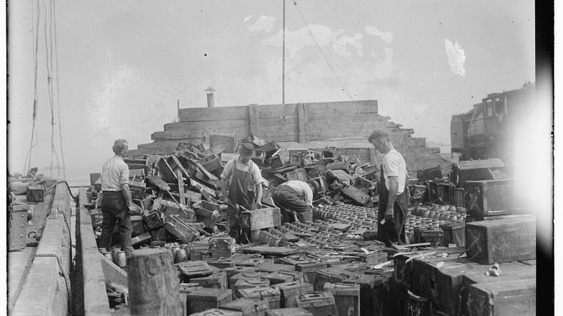 Männer beim Sortieren von Granaten, die von Tauchern in der Nähe von Jersey City nach einer von deutschen Saboteuren ausgelösten Explosion am 30. Juli 1916 auf Black Tom Island im New Yorker Hafen in der Nähe von Liberty Island geborgen wurden.