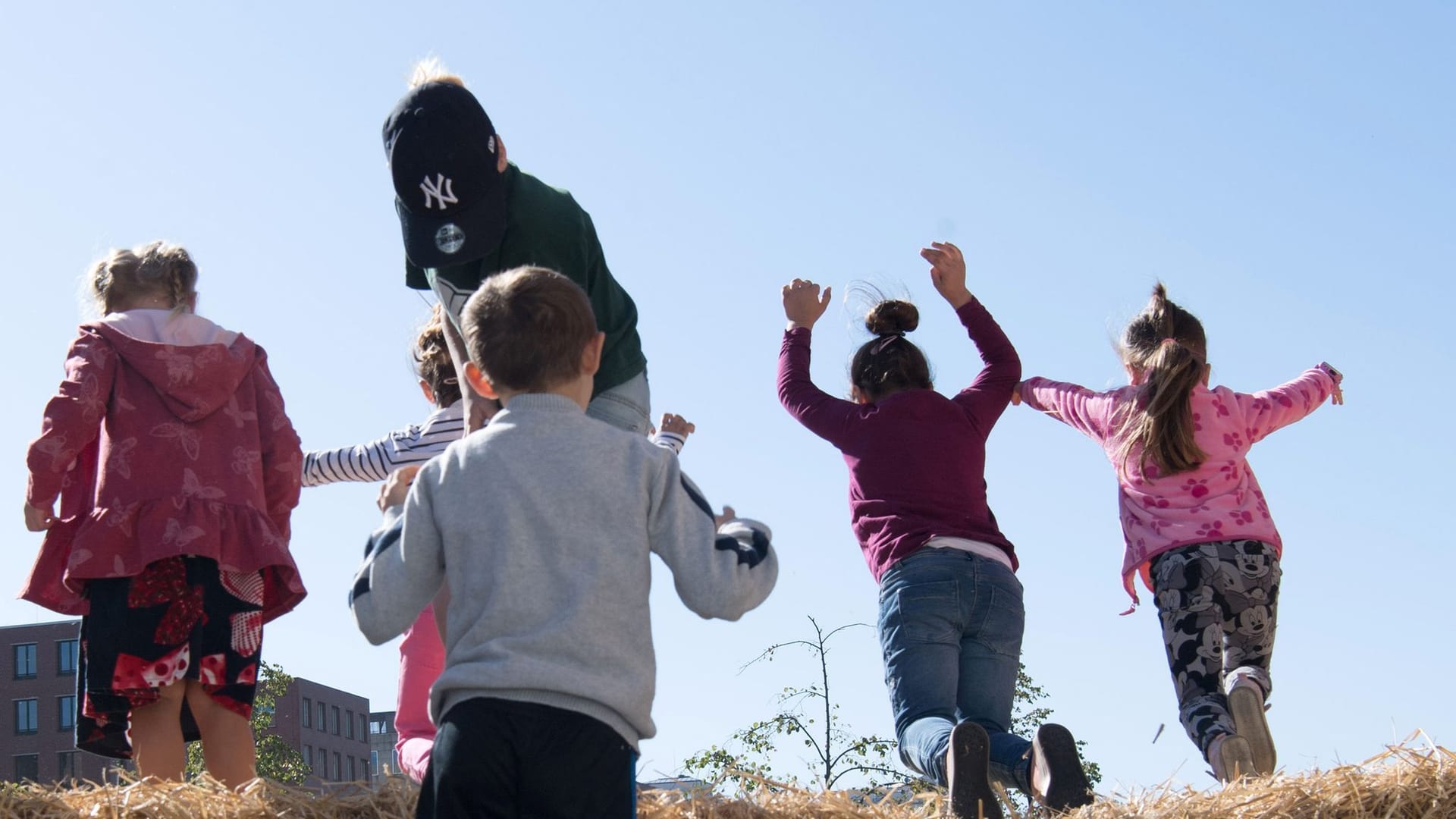 Kinder hüpfen im Heu am Weltkindertag