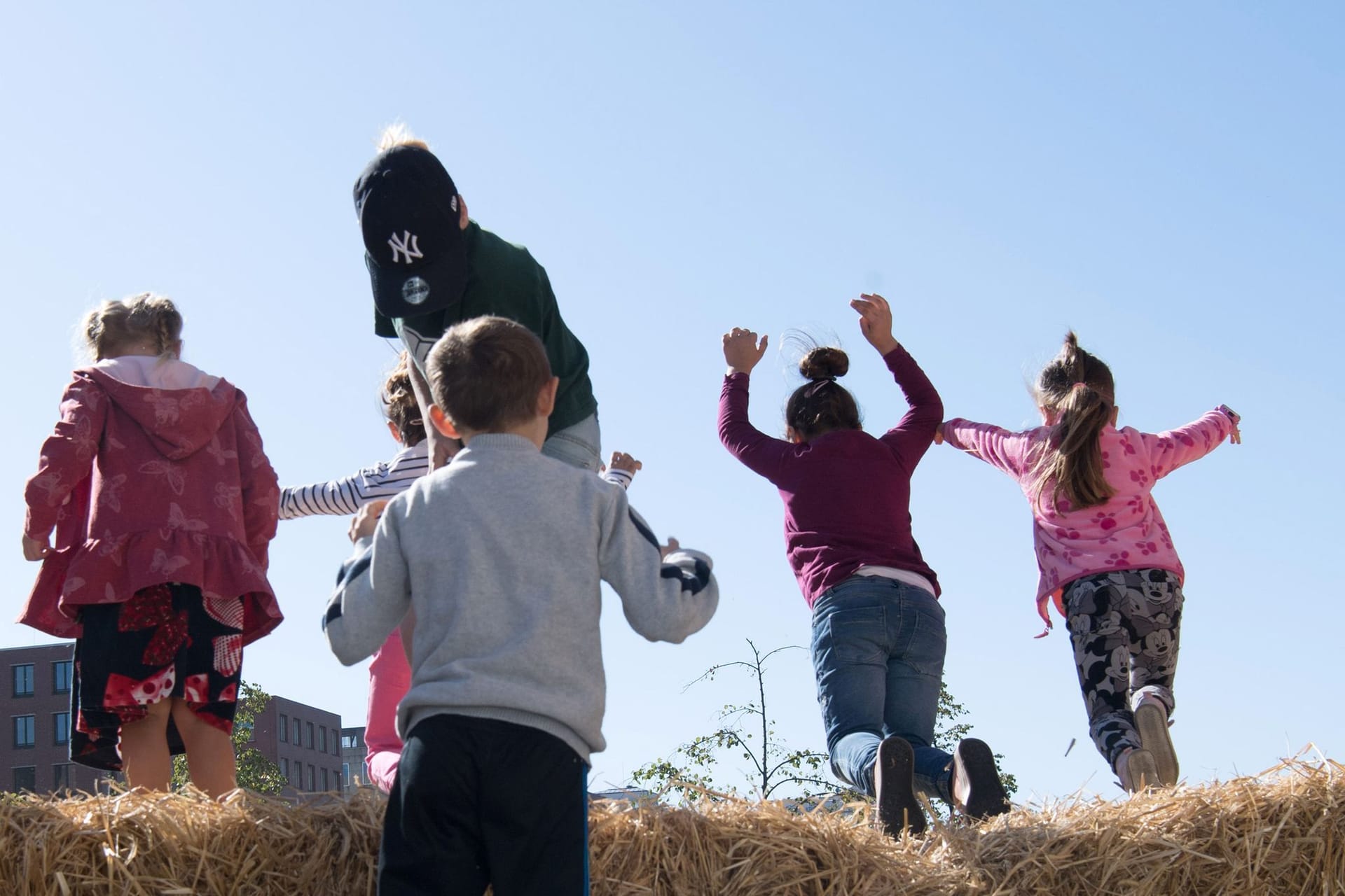 Kinder hüpfen im Heu am Weltkindertag