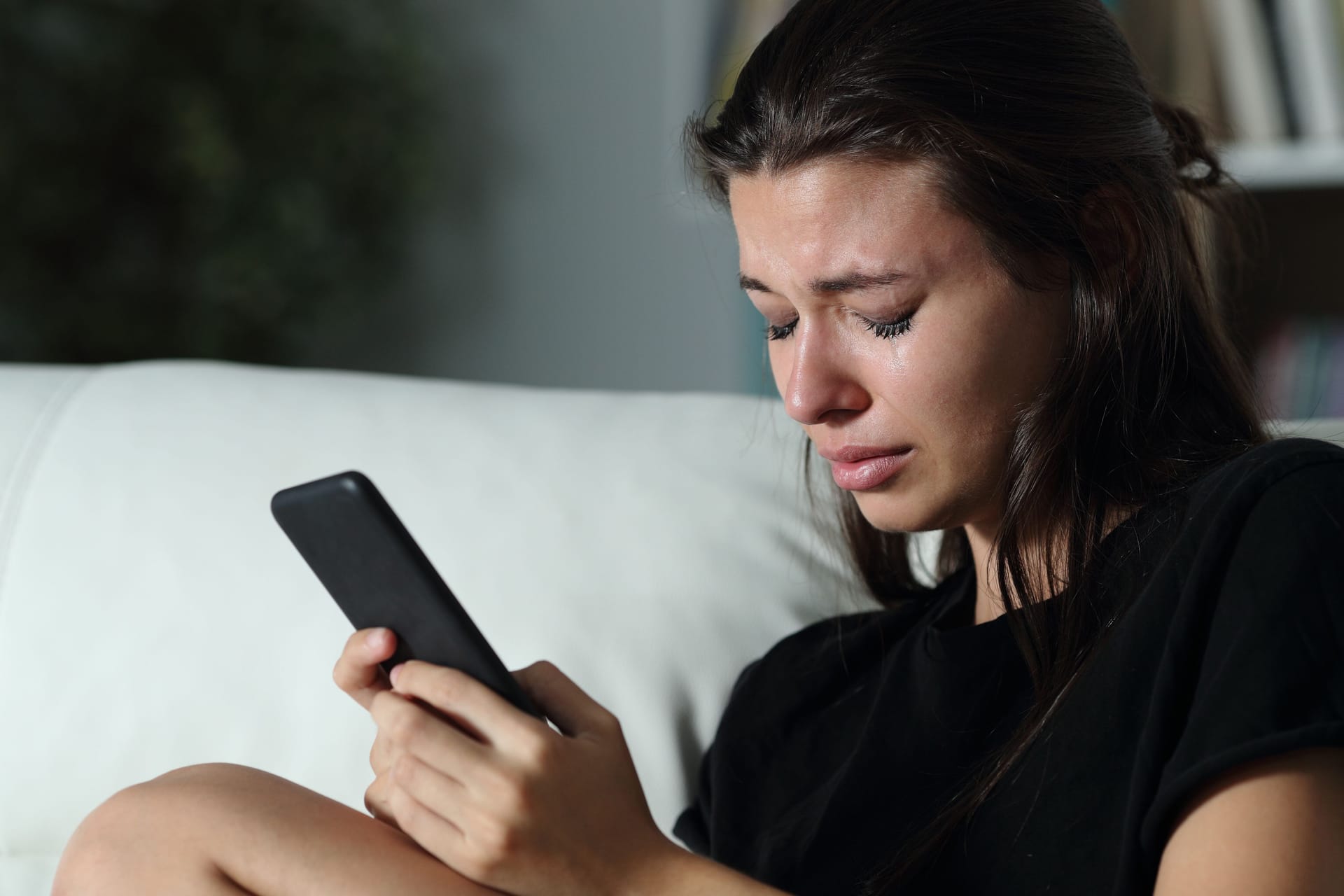 Eine traurige Frau am Handy (Symbolbild): Plötzlicher Kontaktabbruch kann sehr verletzend und verwirrend sein.