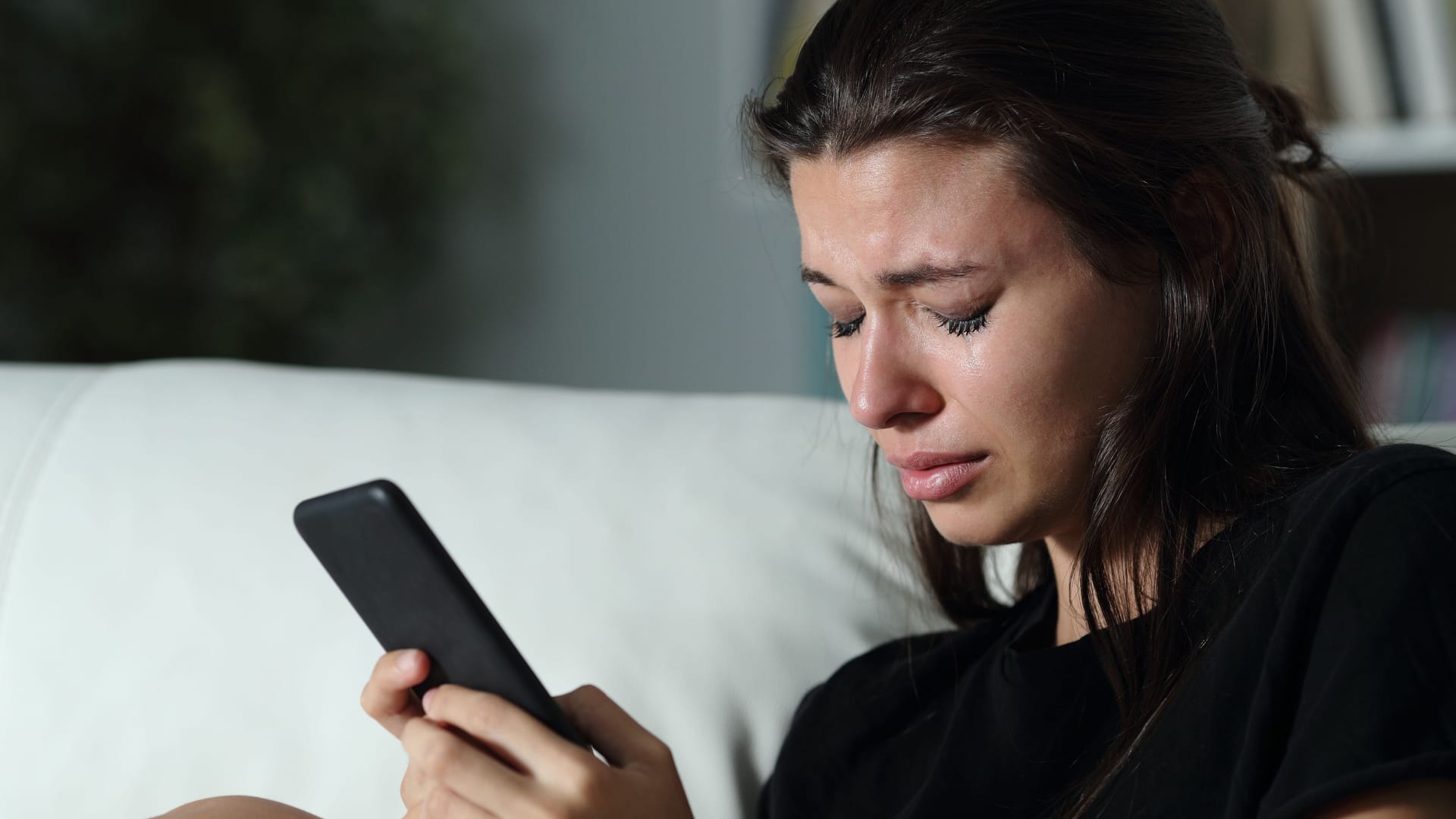 Eine traurige Frau am Handy (Symbolbild): Plötzlicher Kontaktabbruch kann sehr verletzend und verwirrend sein.