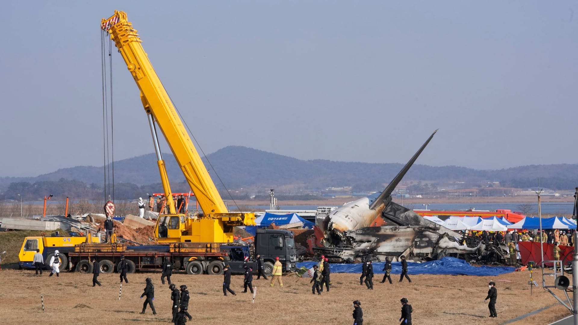 Feuerwehrleute und Mitglieder eines Rettungsteams arbeiten in der Nähe des Flugzeugwracks.