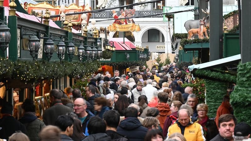 Besucherinnen und Besucher laufen beim Weihnachtsmarkt auf dem Hamburger Rathausmarkt dicht aneinander an den Buden vorbei.