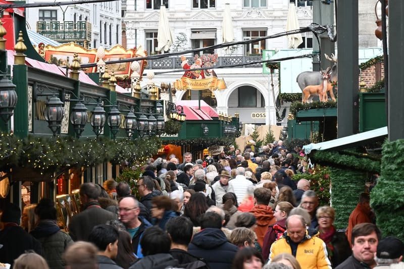 Besucherinnen und Besucher laufen beim Weihnachtsmarkt auf dem Hamburger Rathausmarkt dicht aneinander an den Buden vorbei.