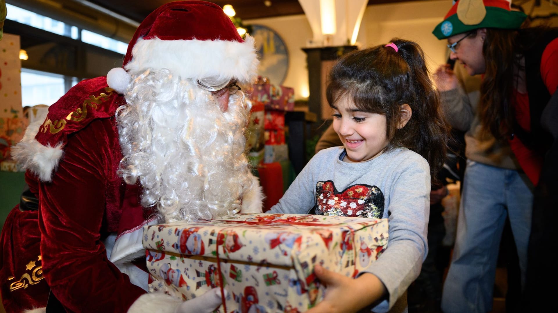 Tamara freut sich beim festlichen Weihnachtsessen für benachteiligte Kinder und Familien im Hofbräu Wirtshaus in Berlin-Mitte über ein Geschenk vom Weihnachtsmann.