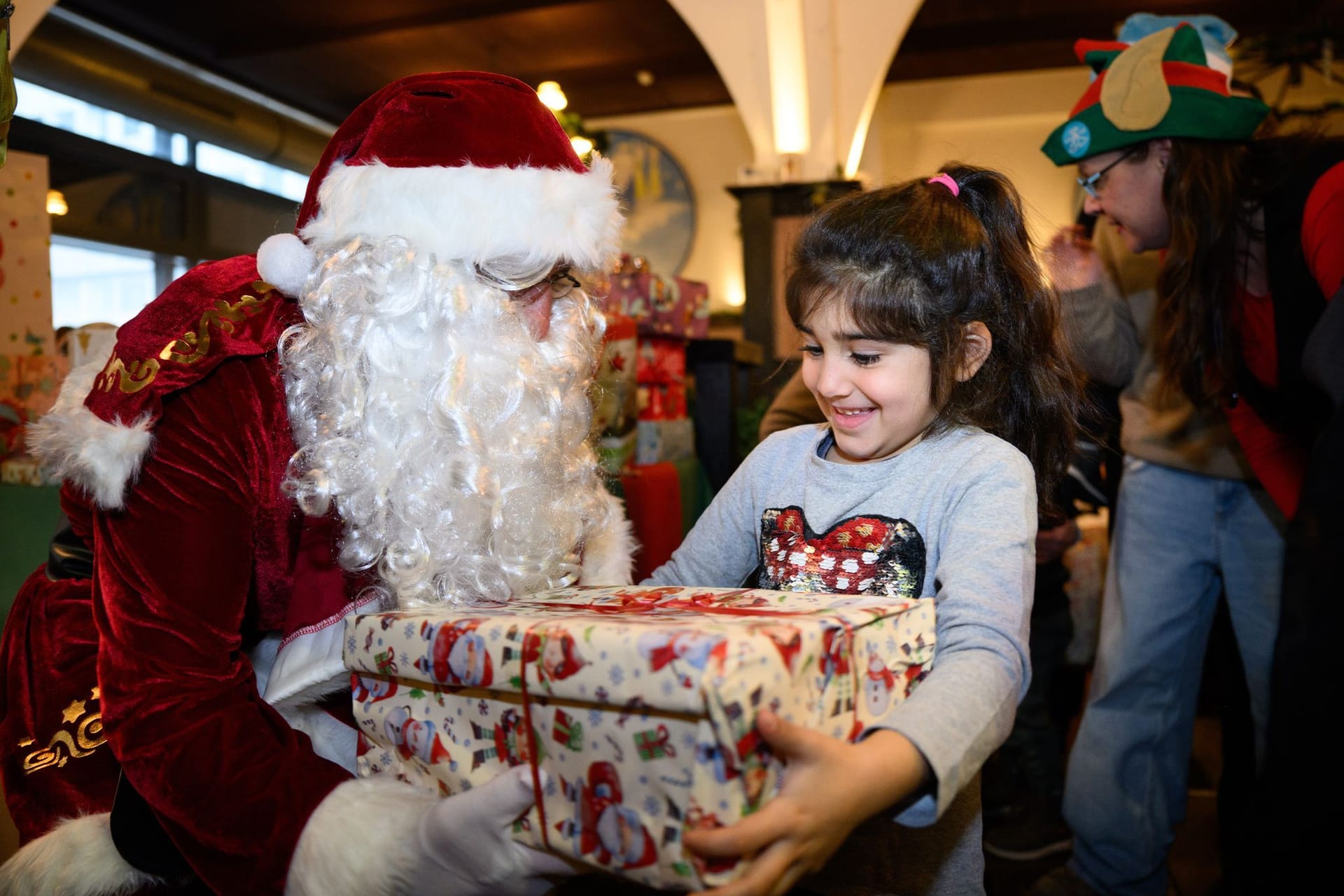 Tamara freut sich beim festlichen Weihnachtsessen für benachteiligte Kinder und Familien im Hofbräu Wirtshaus in Berlin-Mitte über ein Geschenk vom Weihnachtsmann.