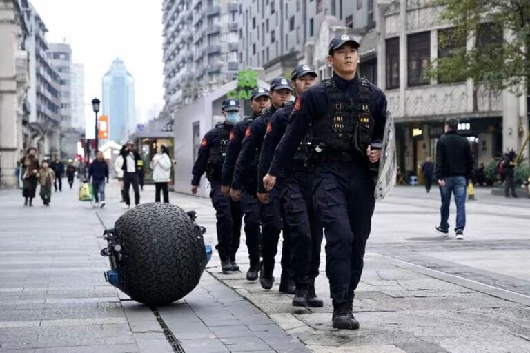 Chinesische Polizisten gehen in Wenzhou mit einem Kugelroboter auf Streife.