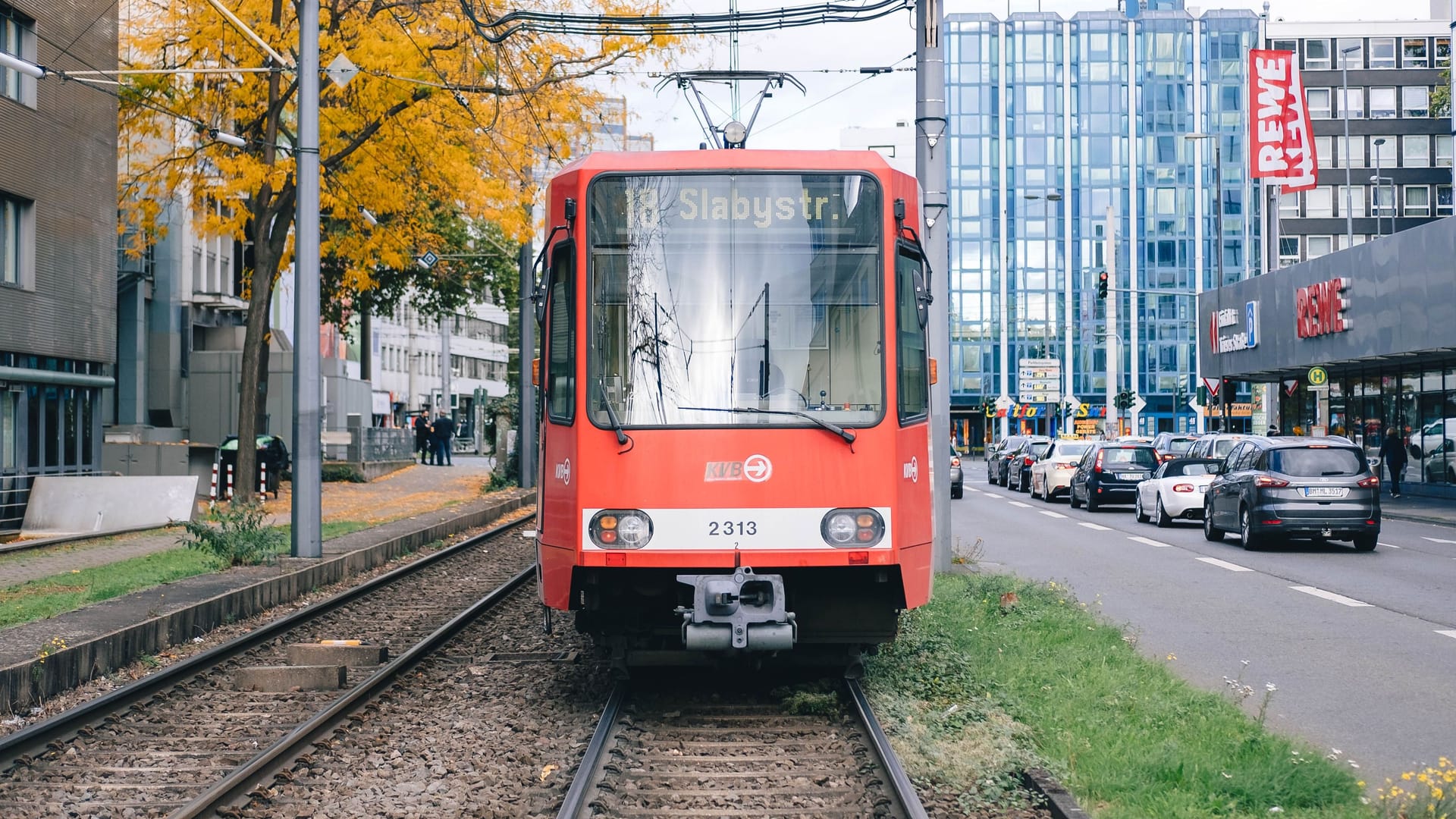 In Cologne, streetcar line 18 towards Slabystrasse is parked in front of Barbarossaplatz, waiting.