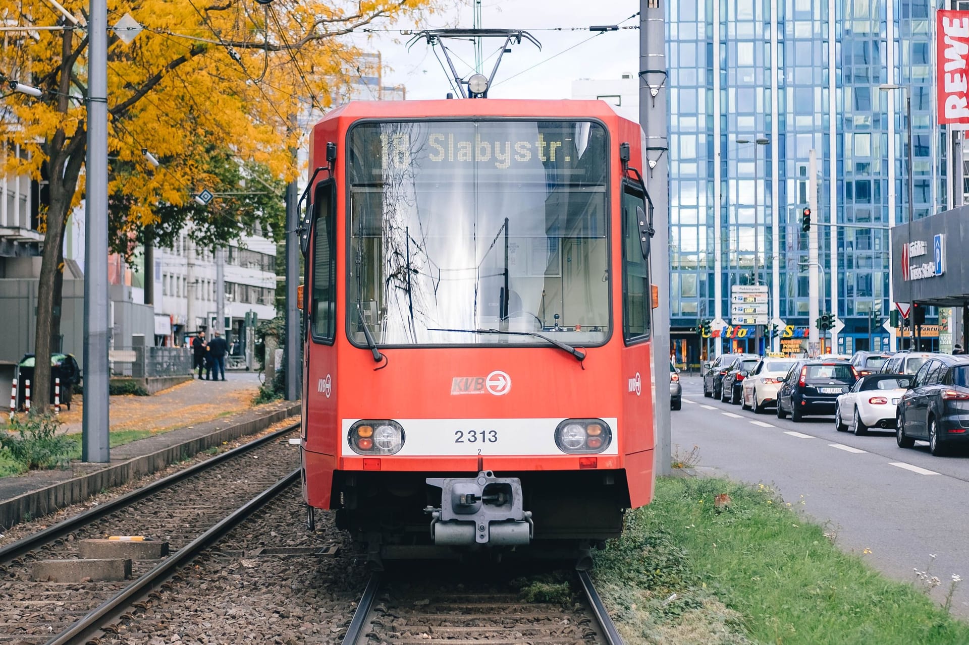 In Cologne, streetcar line 18 towards Slabystrasse is parked in front of Barbarossaplatz, waiting.