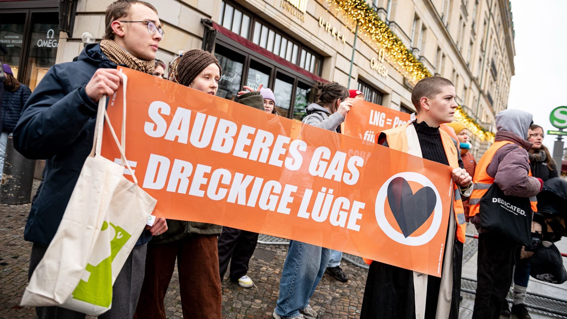 09.12.2024, Berlin: Demonstranten der Letzten Generation stehen vor dem Hotel Adlon mit einem Schild mit der Aufschrift «Sauberes Gas = dreckige Lüge». Seit heute findet dort der World LNG Summit statt, eine internationale Wirtschaftskonferenz zum Thema Flüssiggas.