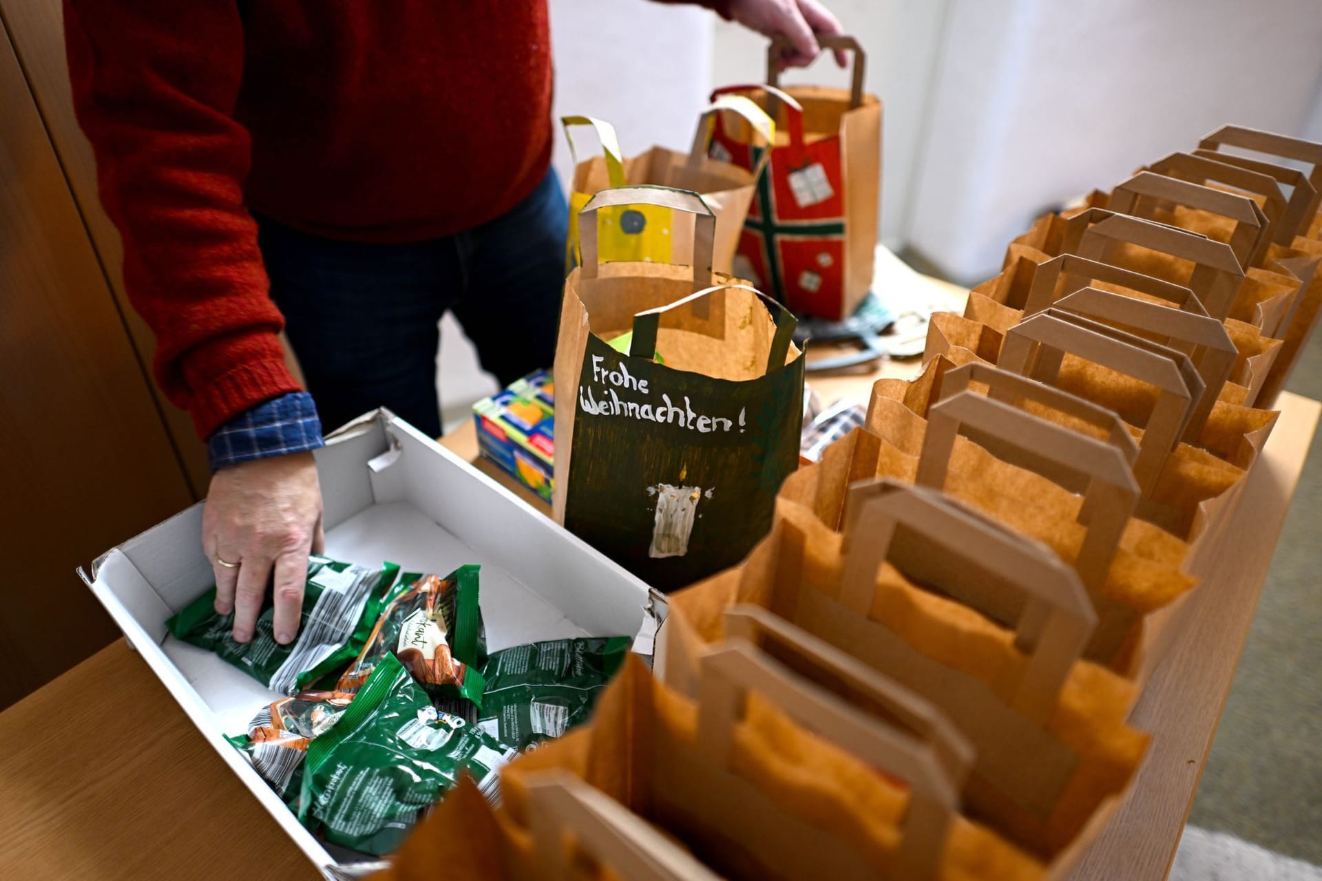 PRODUKTION - 16.12.2024, Bremen: Pastor Christian Fischer bereitet Weihnachtstüten vor, die an die Insassen der Justizvollzugsanstalt Bremen verteilt werden. Die Gefangenen bekommen vor Weihnachten eine Tüte mit Süßigkeiten, Kaffee und einem kleinen Jahreskalender. Die Weihnachtsaktion gibt es seit rund 20 Jahren.