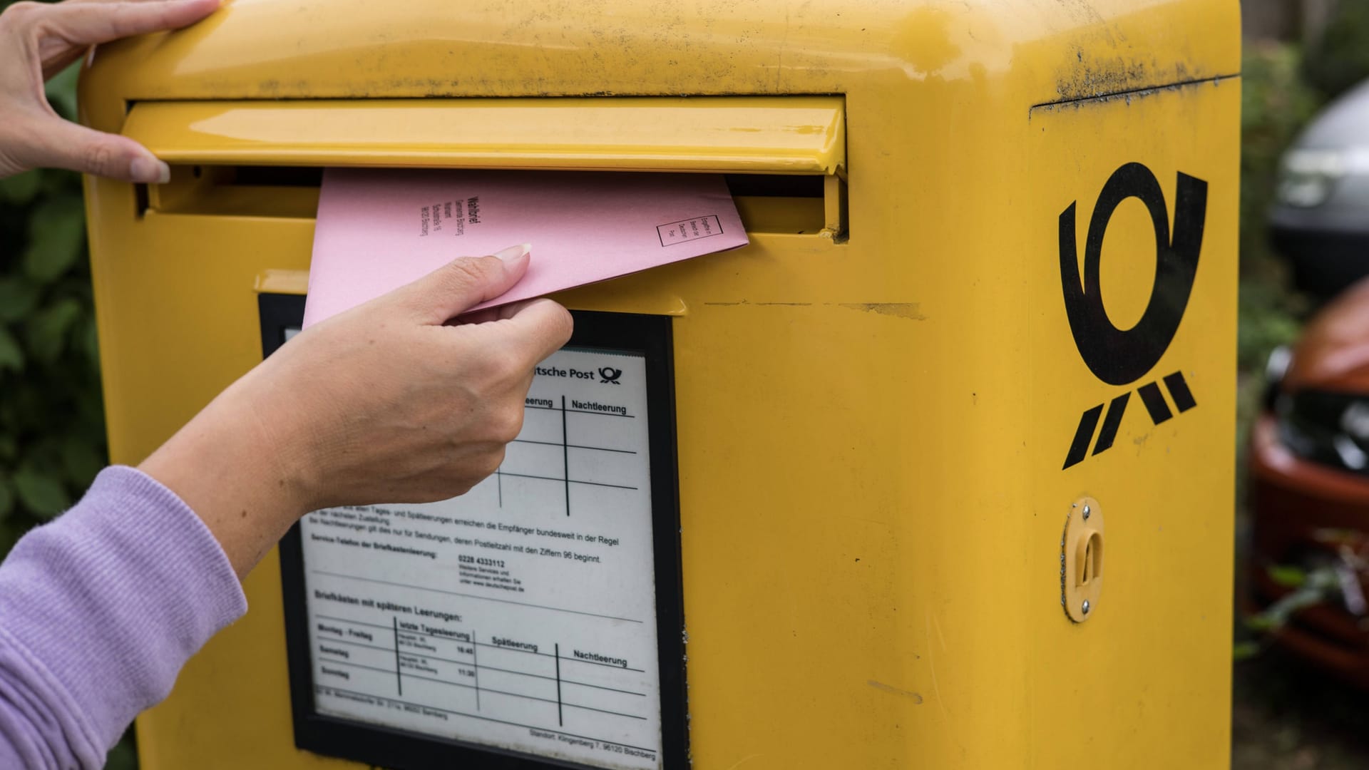 Eine Person wirft ihre Briefwahlunterlagen in einen Briefkasten.