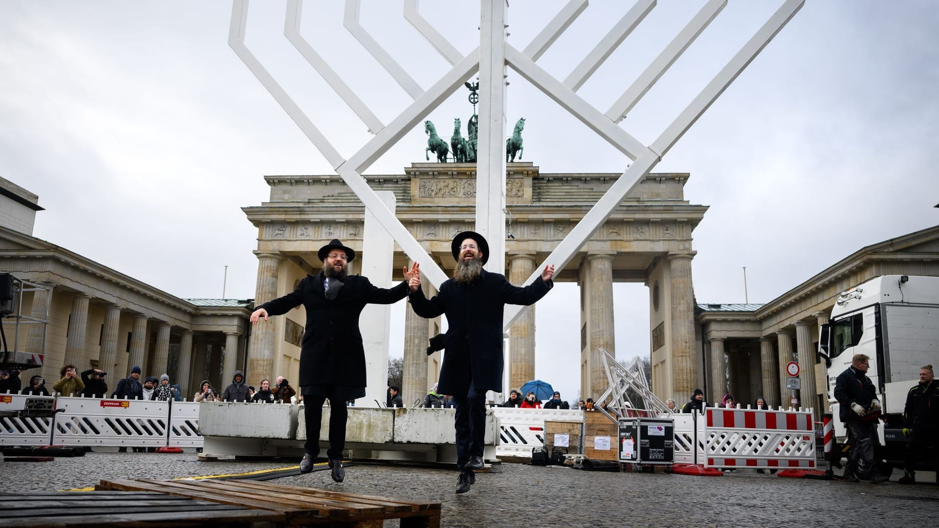 23.12.2024, Berlin: Rabbiner Yehuda Teichtal (l), Vorsitzender der Jüdischen Gemeinde Chabad Berlin, und Rabbi Shmuel Segal tanzen bei der Einweihung des nach Veranstalterangaben größten Chanukka-Leuchters Europas auf dem Pariser Platz. Der zehn Meter hohe Chanukka-Leuchter wird seit 19 Jahren von der Jüdischen Gemeinde Chabad Berlin vor dem Brandenburger Tor aufgestellt und während der Dauer der Feiertage täglich gezündet. Das achttägige jüdische Lichterfest Chanukka beginnt am 25.12.2024.