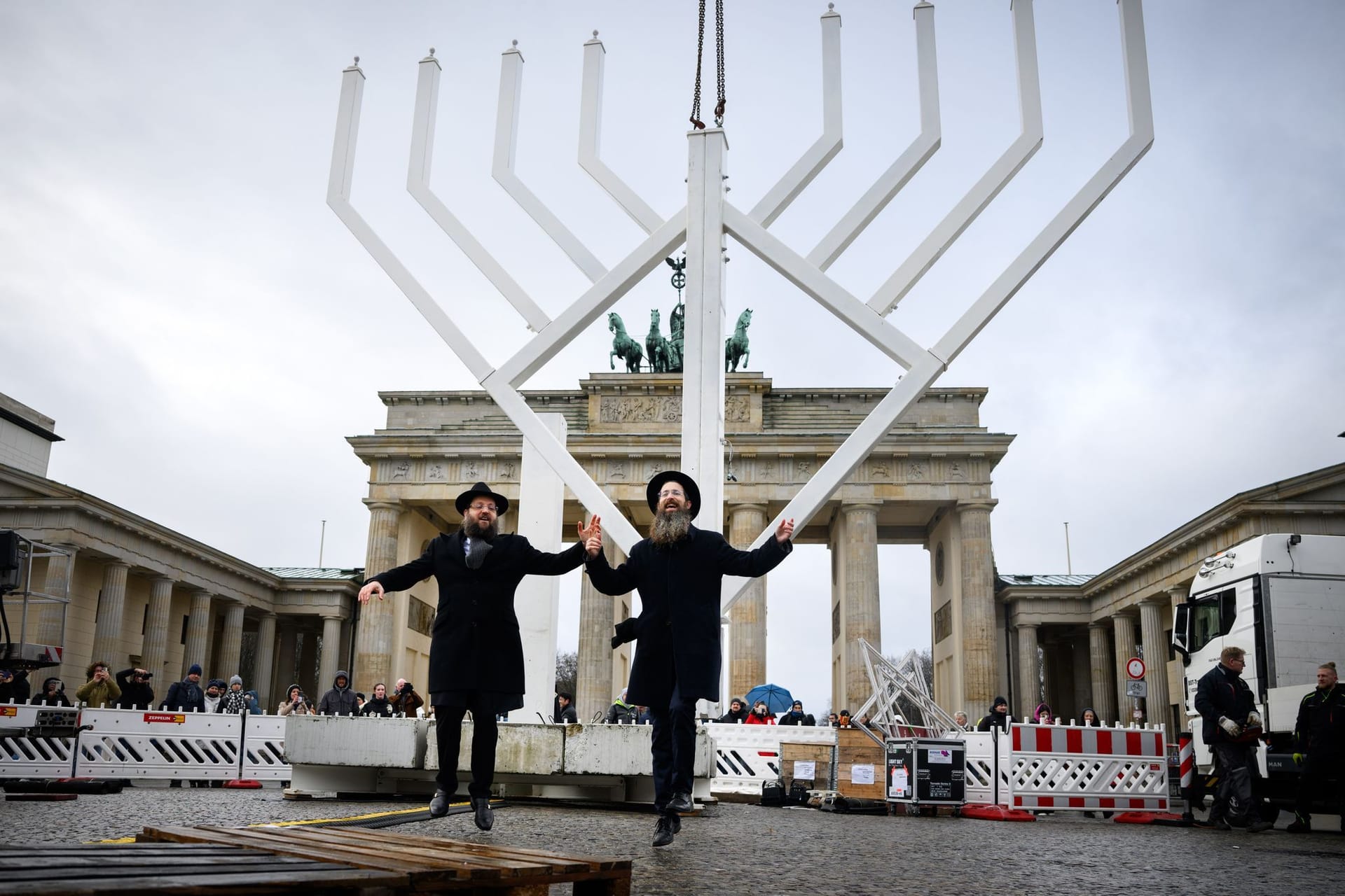 23.12.2024, Berlin: Rabbiner Yehuda Teichtal (l), Vorsitzender der Jüdischen Gemeinde Chabad Berlin, und Rabbi Shmuel Segal tanzen bei der Einweihung des nach Veranstalterangaben größten Chanukka-Leuchters Europas auf dem Pariser Platz. Der zehn Meter hohe Chanukka-Leuchter wird seit 19 Jahren von der Jüdischen Gemeinde Chabad Berlin vor dem Brandenburger Tor aufgestellt und während der Dauer der Feiertage täglich gezündet. Das achttägige jüdische Lichterfest Chanukka beginnt am 25.12.2024.