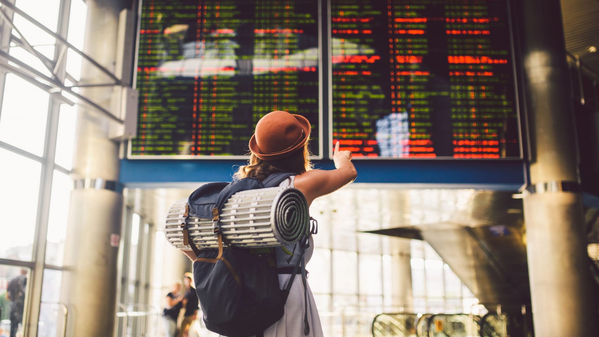 Am Flughafen: Eine junge Frau kontrolliert vor der Anzeigetafel ihren Flugplan.