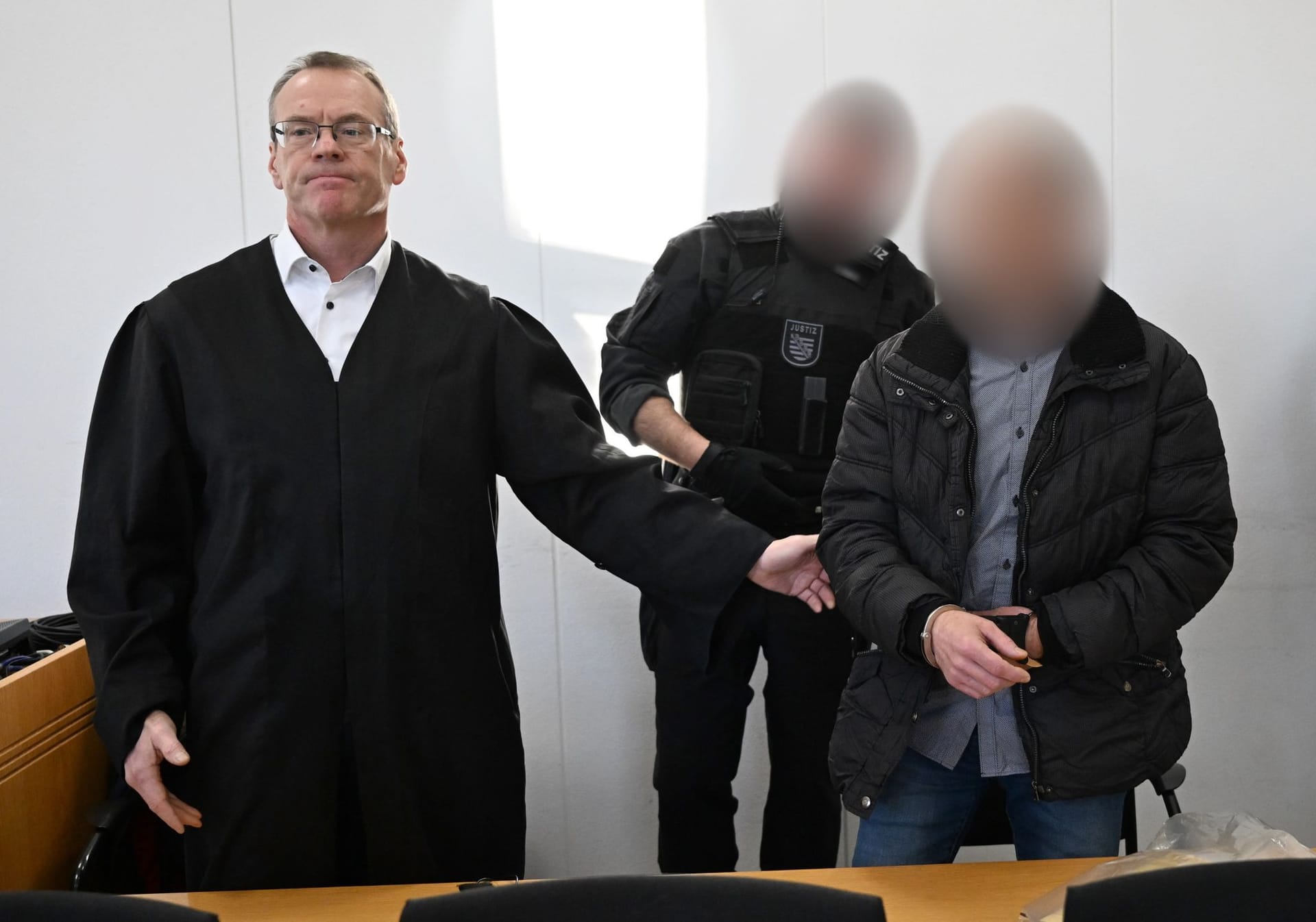 Der wegen Mordes an der neunjährigen Valeriia Angeklagte (r) wird im Landgericht von einem Justizbeamten neben seinem Verteidiger Jörg Neuber (l) vorgeführt.