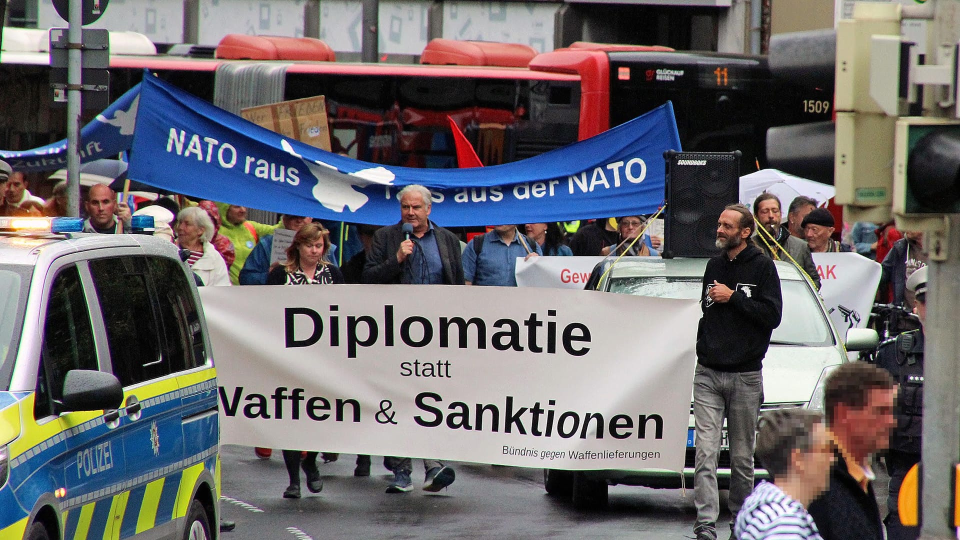 Mona Aranea und Andrej Hunko am 5. August 2023 hinter dem Transparent einer Demonstration in Aachen, an der rund 45 Personen sowohl aus dem linken als auch dem rechten Spektrum teilnahmen.