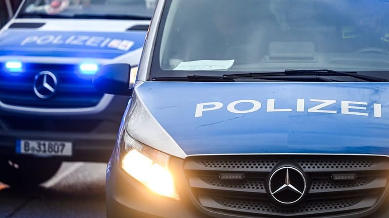 Polizeiautos mit eingeschalteten Scheinwerfern und Blaulicht.