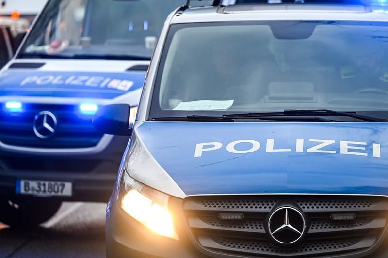 Polizeiautos mit eingeschalteten Scheinwerfern und Blaulicht.