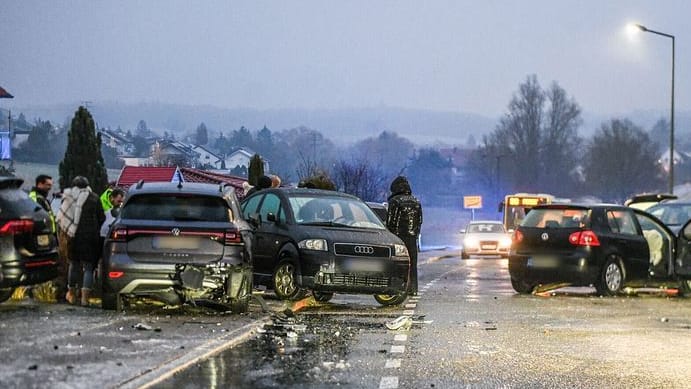 Nach einem Unfall bei Glatteis mit mehreren Fahrzeugen stehen Helfer und Beteiligte an den Autos auf einer Straße: Bundesweit kam es zu Hunderten Unfällen.