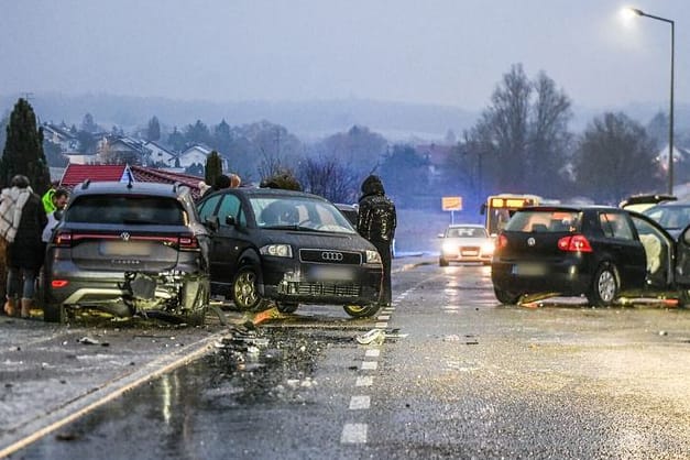 Nach einem Unfall bei Glatteis mit mehreren Fahrzeugen stehen Helfer und Beteiligte an den Autos auf einer Straße: Bundesweit kam es zu Hunderten Unfällen.