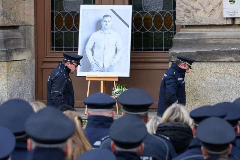 Polizisten stehen zum Gedenken des im Einsatz getöteten Kollegen Maximilian Stoppa für eine Schweigeminute vor dem Polizeipräsidium, an dem ein Porträtfoto des Kollegen aufgestellt ist. Der 32 Jahre alte Polizist wurde am 7. Januar 2024 in Lauchhammer im Grenzgebiet zu Sachsen bei einem Einsatz gegen mutmaßliche Autodiebe getötet.