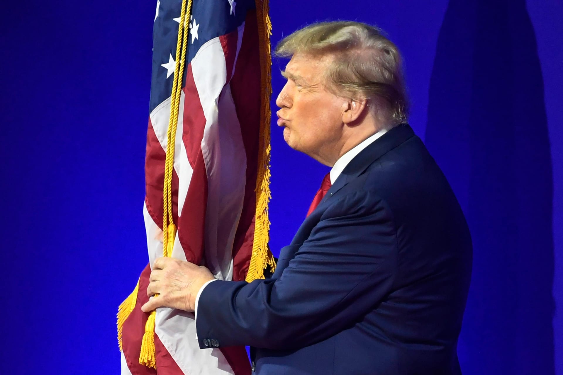 Donald Trump umarmt und küsst die US-Flagge bei der Conservative Political Action Conference CPAC im Jahr 2024.