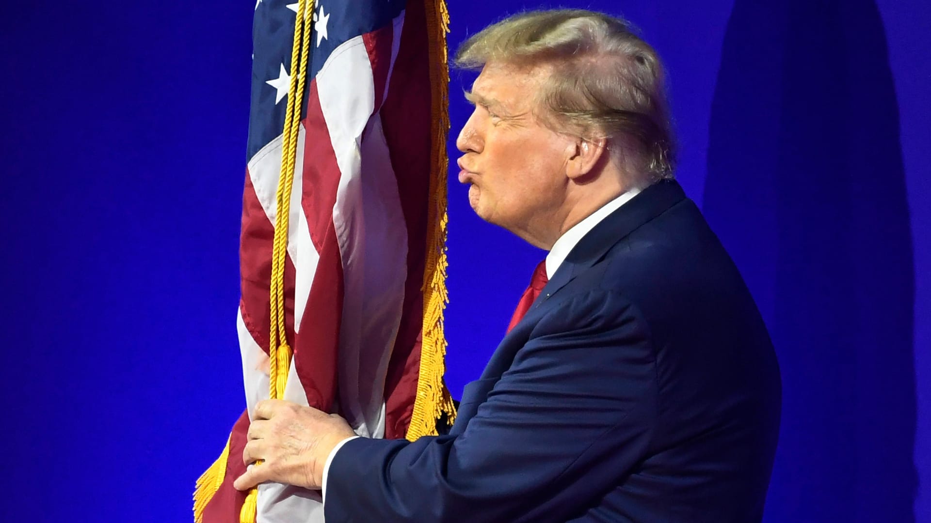 Donald Trump umarmt und küsst die US-Flagge bei der Conservative Political Action Conference CPAC im Jahr 2024.