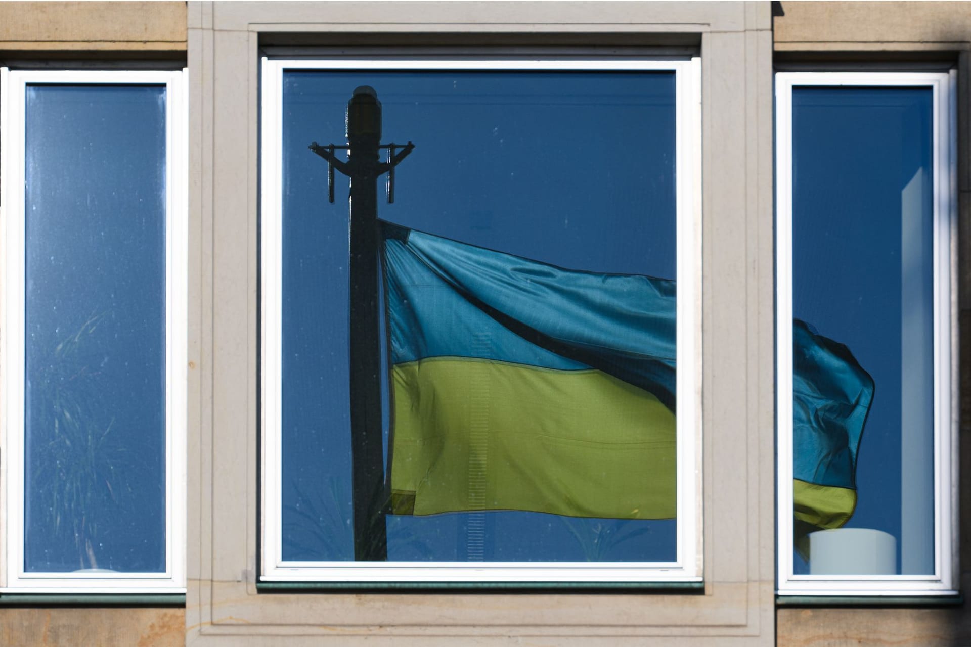 Eine Fahne der Ukraine spiegelt sich in einem Fenster