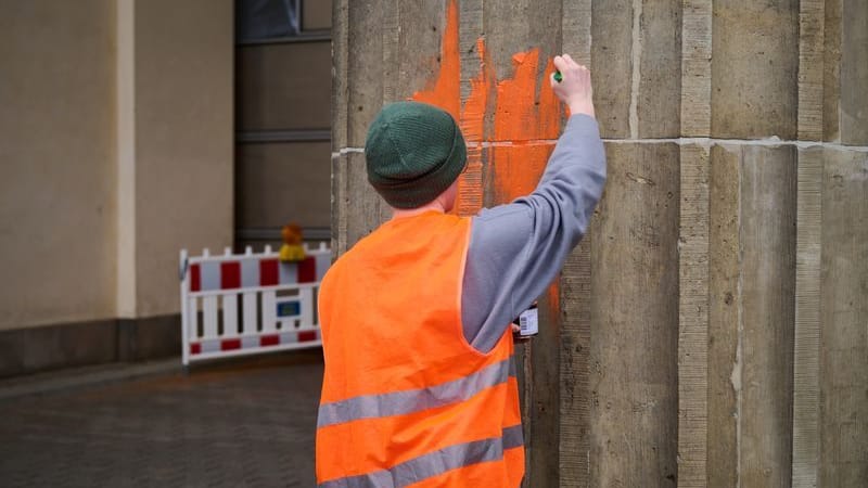 Eine Klimaaktivistin bemalt das Brandenburger Tor mit oranger Farbe.