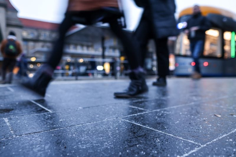 Passanten gehen über die feuchte Haltestelle vor dem Hauptbahnhof. Der für heute vorhergesagte Regen fällt auf gefrorenen Boden und kann für gefährliches Glatteis sorgen. Für Teile aller Bundesländer galten am Morgen deswegen Unwetterwarnungen des Deutschen Wetterdienstes (DWD).