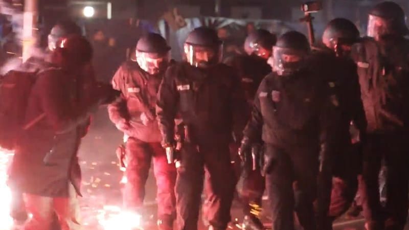 Einsatzkräfte der Polizei stehen in der Silvesternacht zwischen brennendem Feuerwerk in Neukölln.