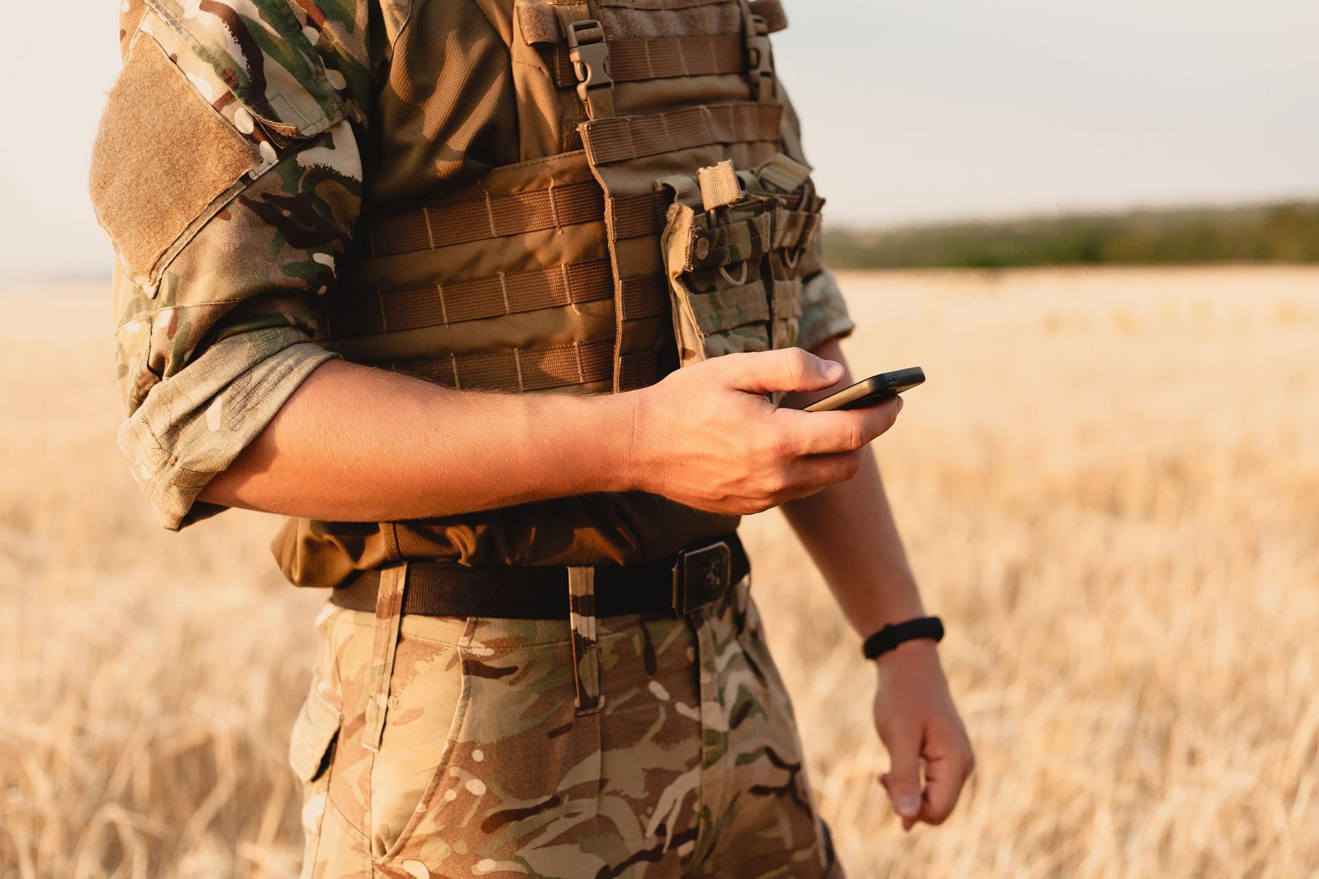 Mid section of military soldier using mobile phone