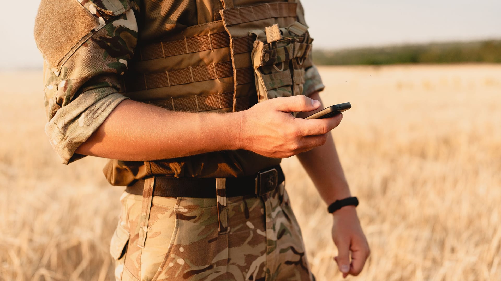 Mid section of military soldier using mobile phone