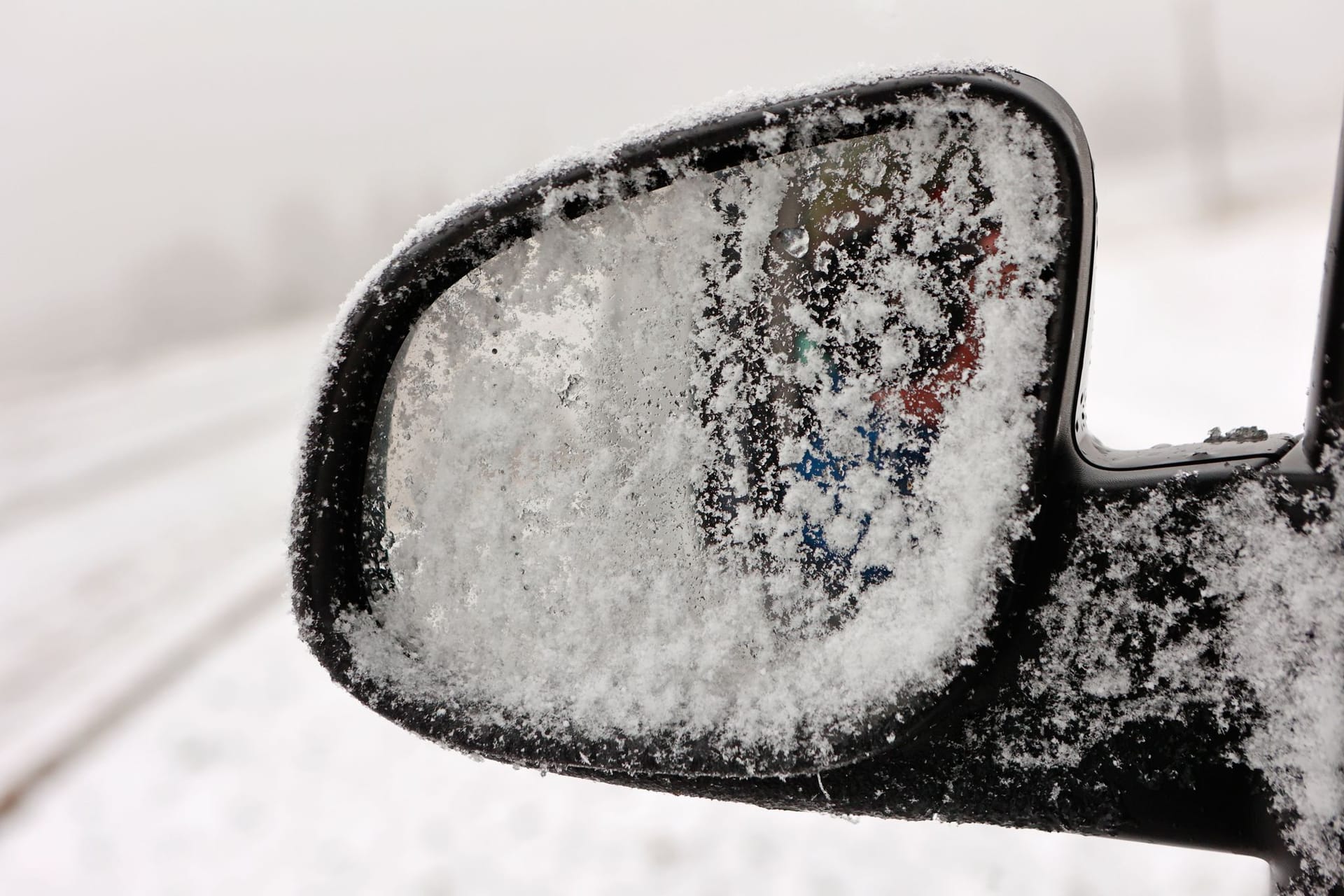 Blick auf einen schneebedeckten Außenspiegel: In Sachsen ist es glatt auf den Straßen.