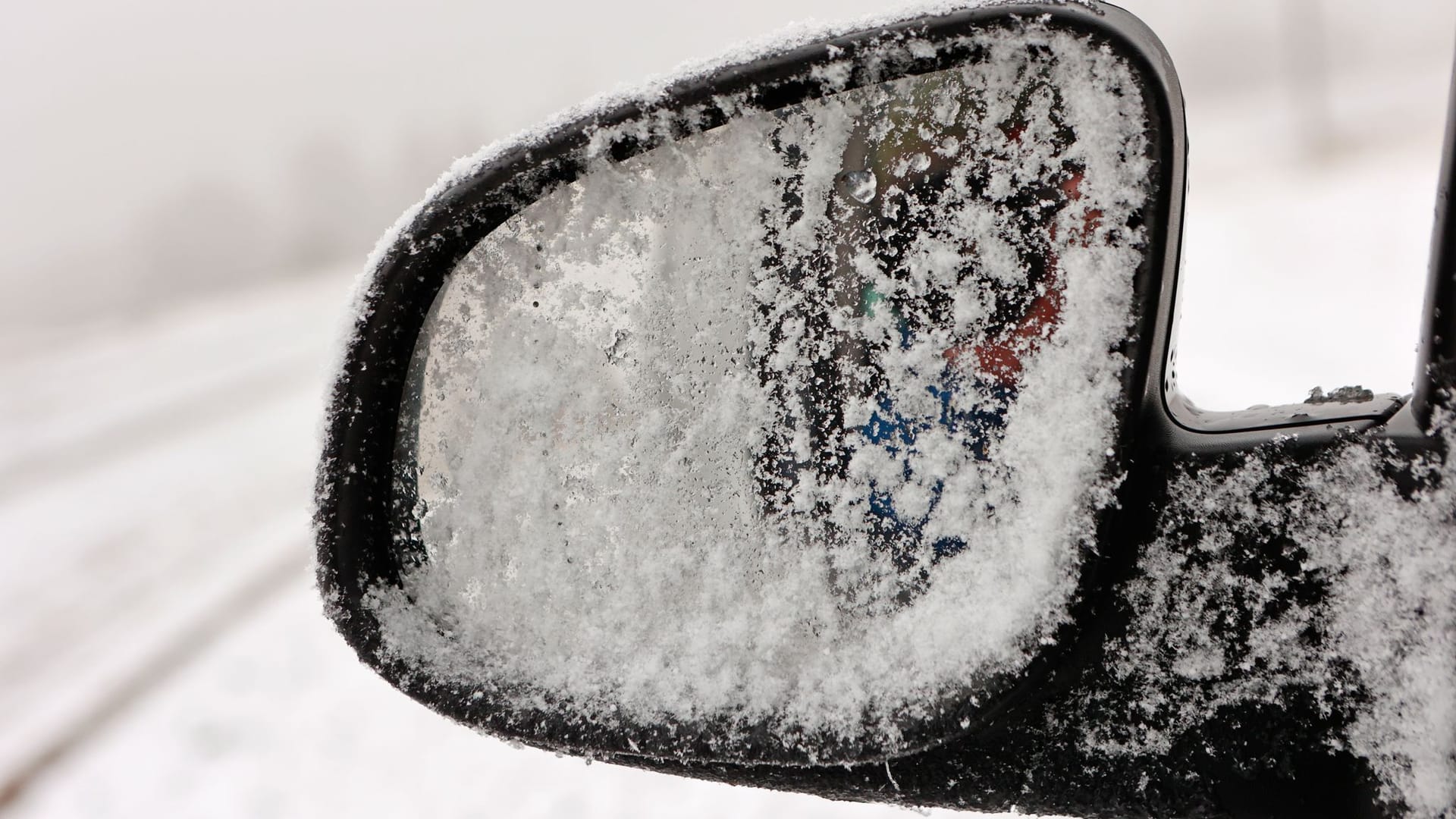 Blick auf einen schneebedeckten Außenspiegel: In Sachsen ist es glatt auf den Straßen.