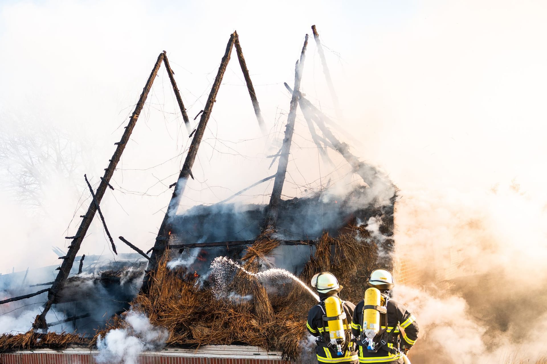 Einsatzkräfte löschen den Brand: Ein Reetdachhaus fing in Hamburg-Kirchwerder Feuer.