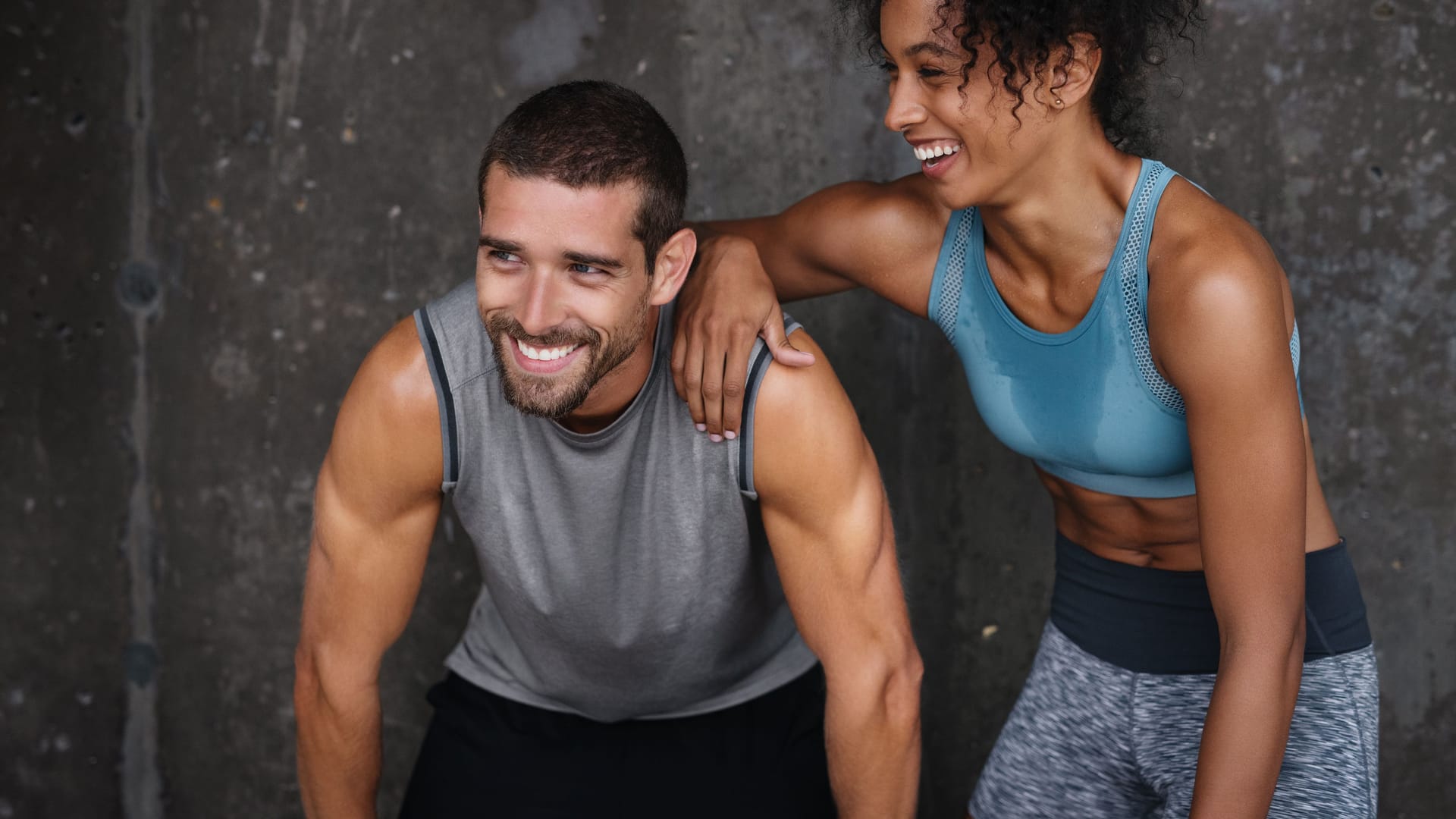 Ein Mann und eine Frau in Sportkleidung lachen.