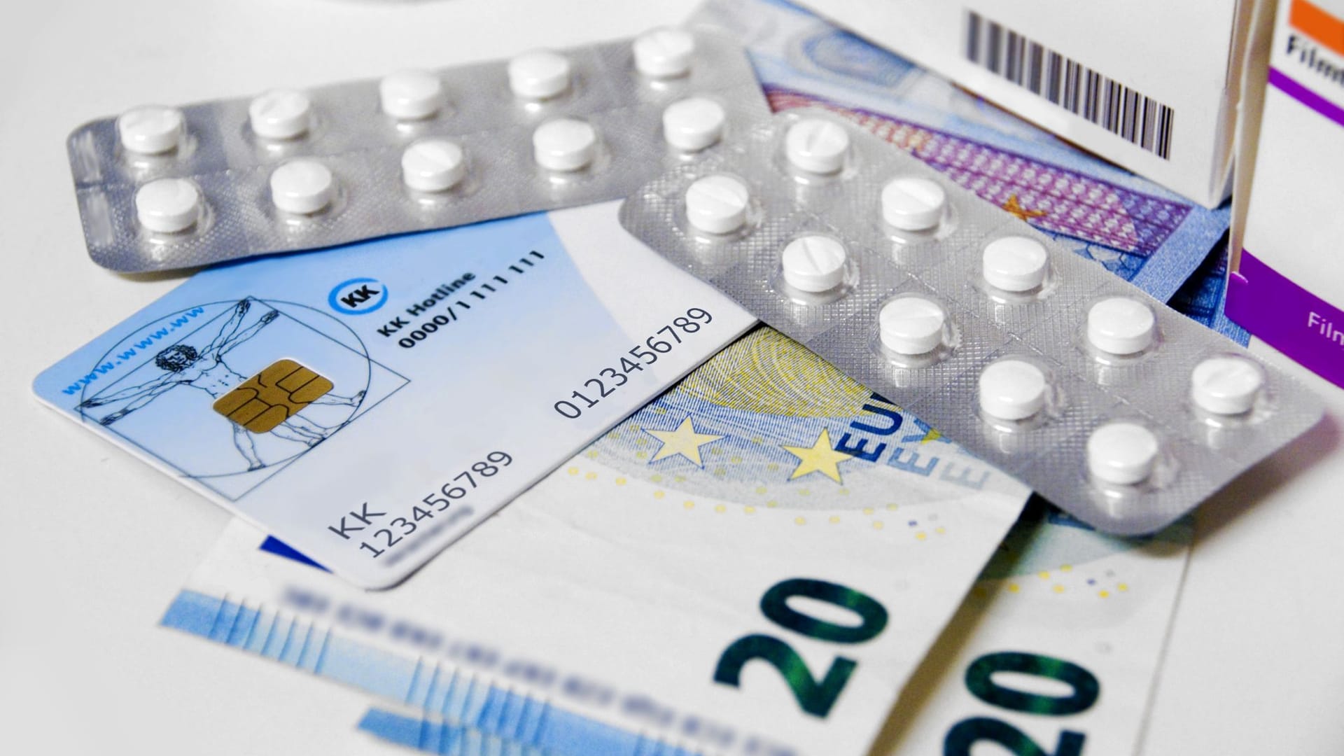 Gesundheitskarte, Tabletten und Geld liegen auf einem Tisch