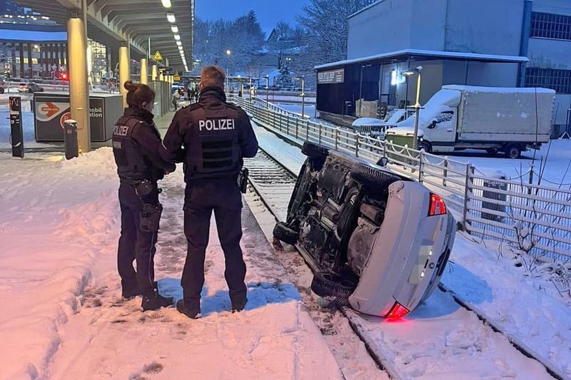 Ein Auto liegt umgekippt auf einem verschneiten Bahngleis in Lüdenscheid.