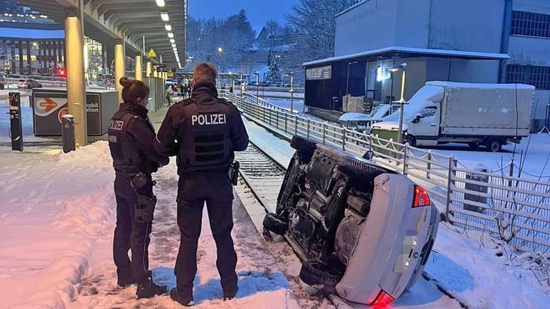 Ein Auto liegt umgekippt auf einem verschneiten Bahngleis in Lüdenscheid.