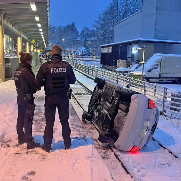 Ein Auto liegt umgekippt auf einem verschneiten Bahngleis in Lüdenscheid.