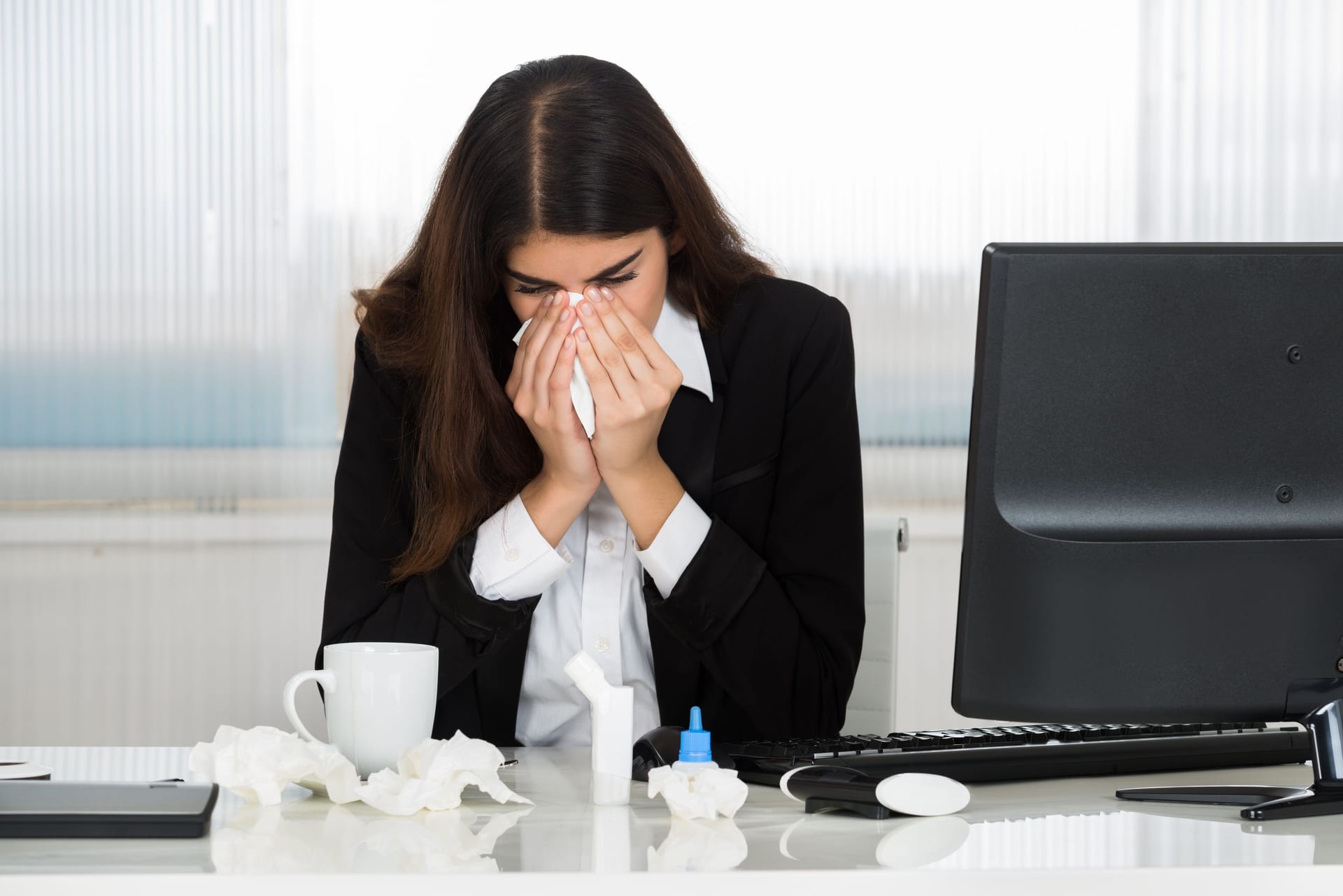 Eine Arbeitnehmerin erscheint krank im Büro (Symbolbild): Karenztage werden kontrovers diskutiert.