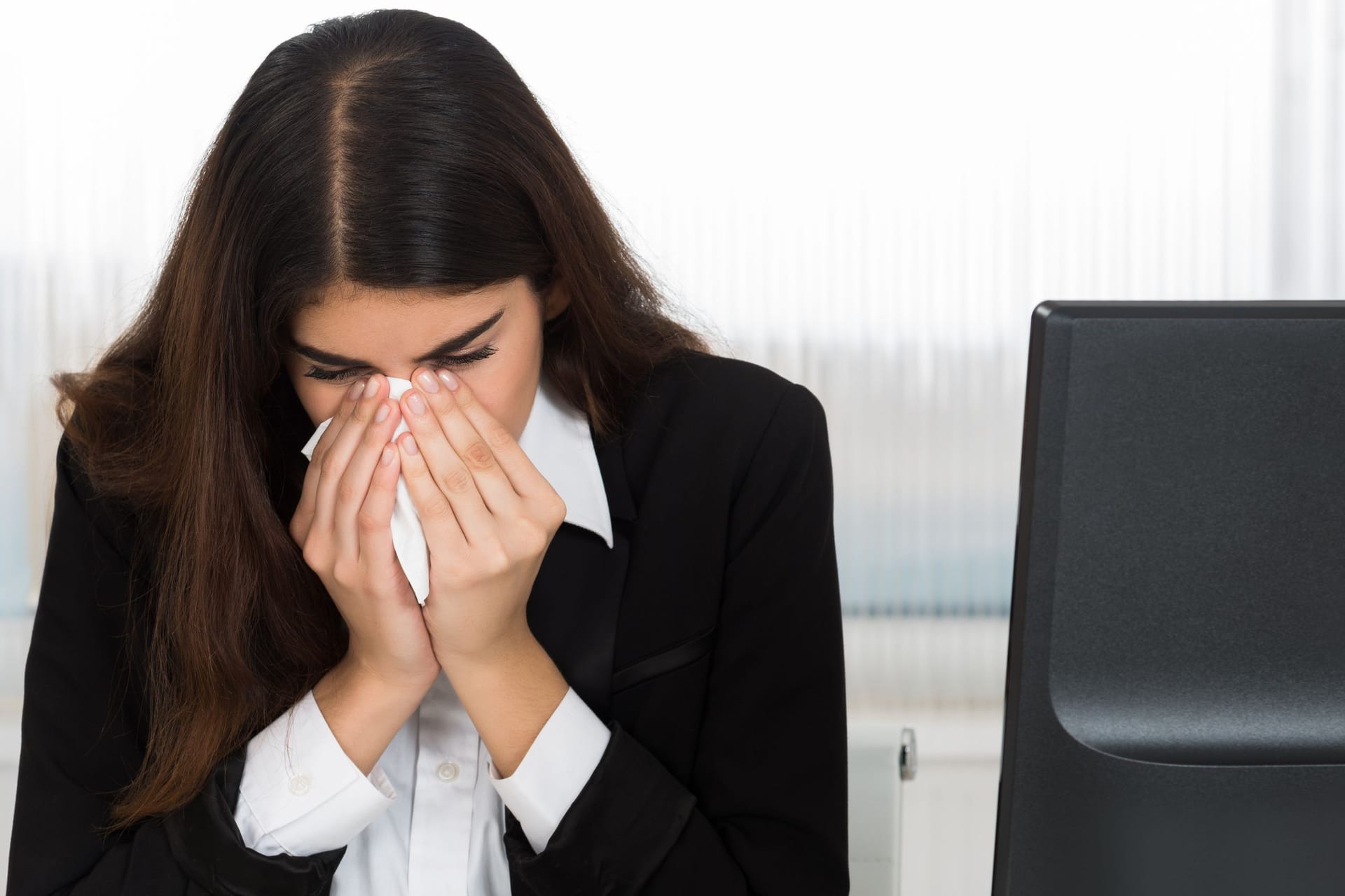 Eine Arbeitnehmerin erscheint krank im Büro (Symbolbild): Karenztage werden kontrovers diskutiert.