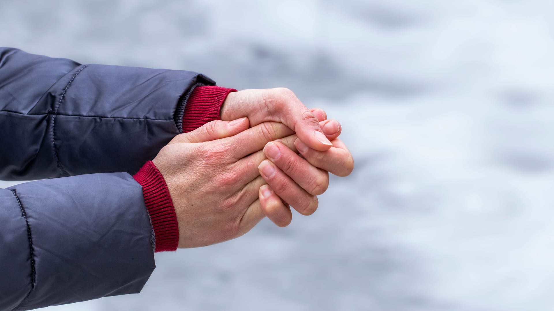 Eine Frau umfasst ihre kalten Hände: Wer Hände und Füße bei feuchter Kälte nicht ausreichend schützt, riskiert womöglich Frostbeulen.