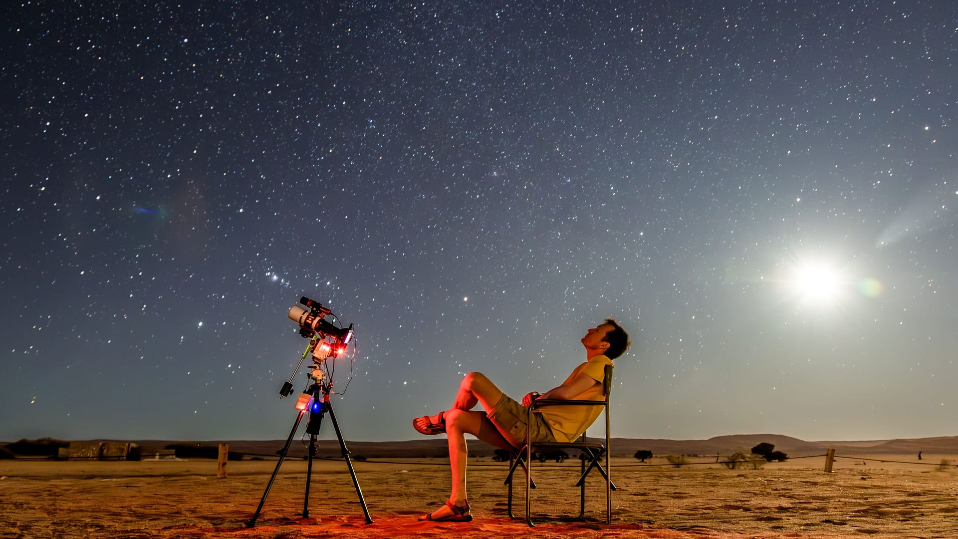 Namibia: Ein Mann mit Teleskop beobachtet, wie die Nacht hereinbricht.